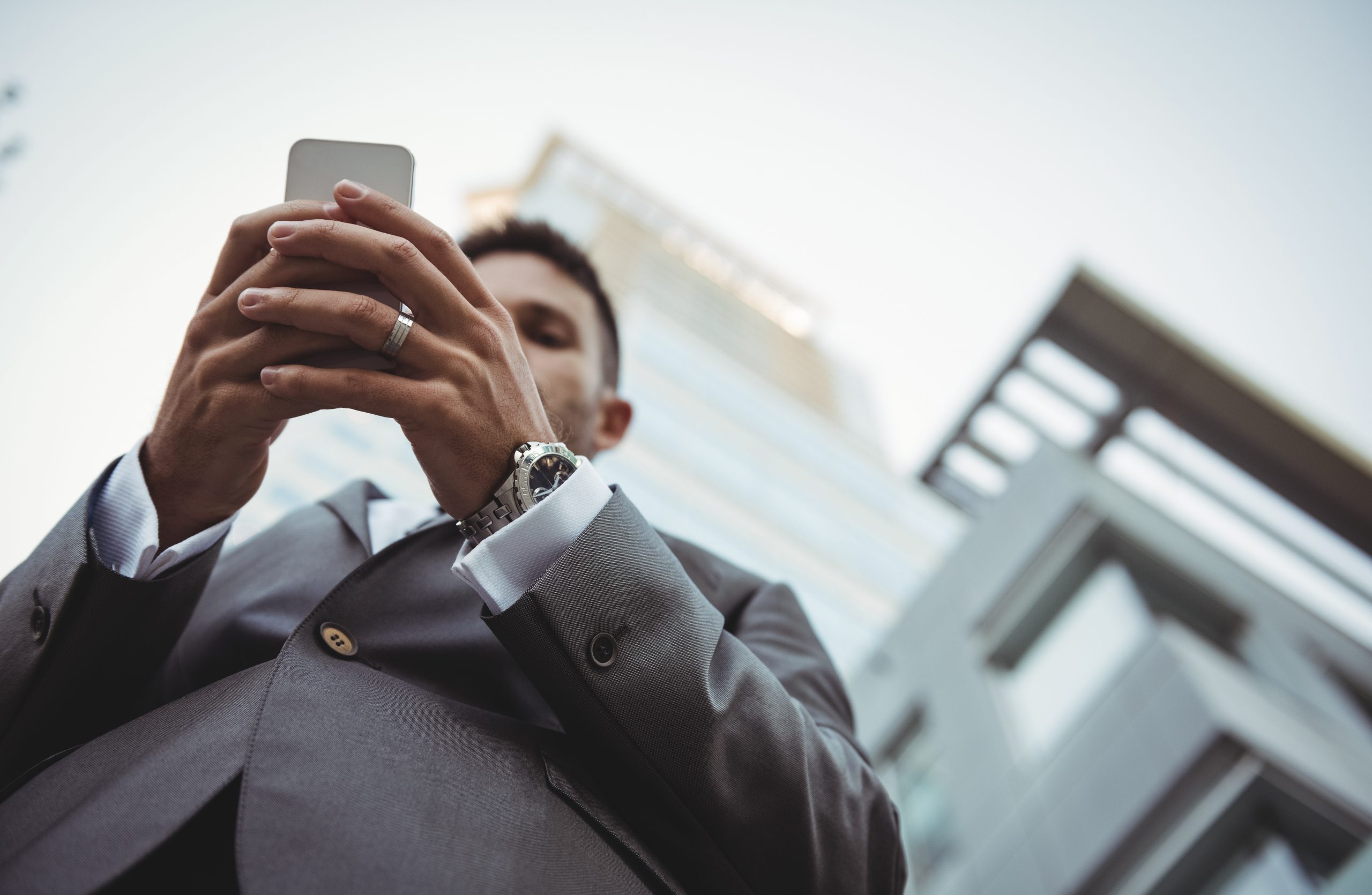 Businessman using mobile phone near office building